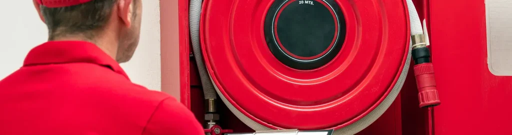 Fire hose reel cabinet with technician inspecting safety equipment